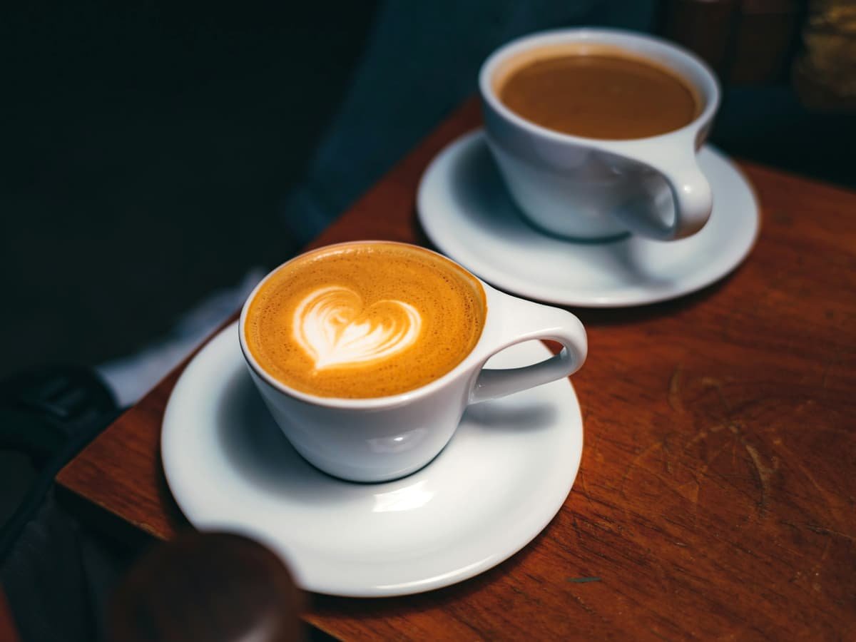 Two cups of coffee sitting on top of a wooden table: date idea in Alberta