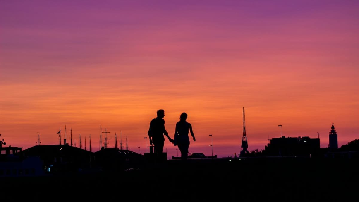 A couple of people walking across a field at sunset, date night in Alberta
