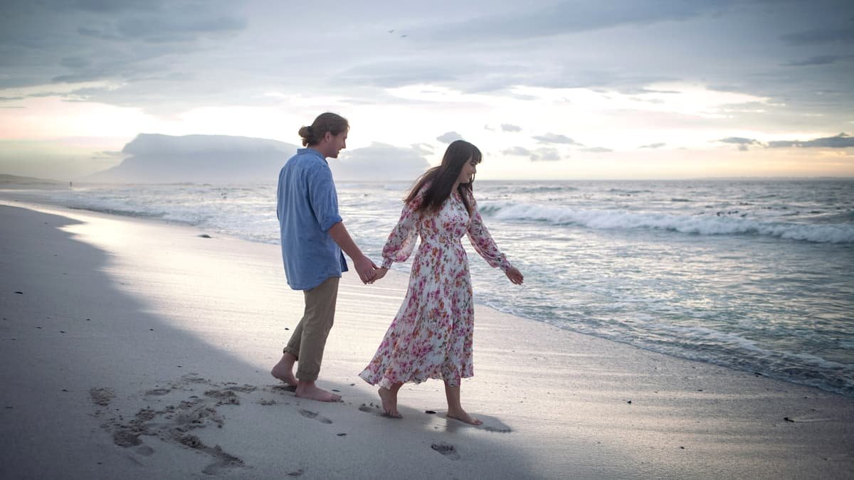 A man and a woman holding hands on a beach, date night in Alberta