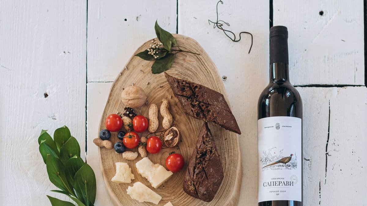 Red wine, cheese, and snacks on a rustic wooden board