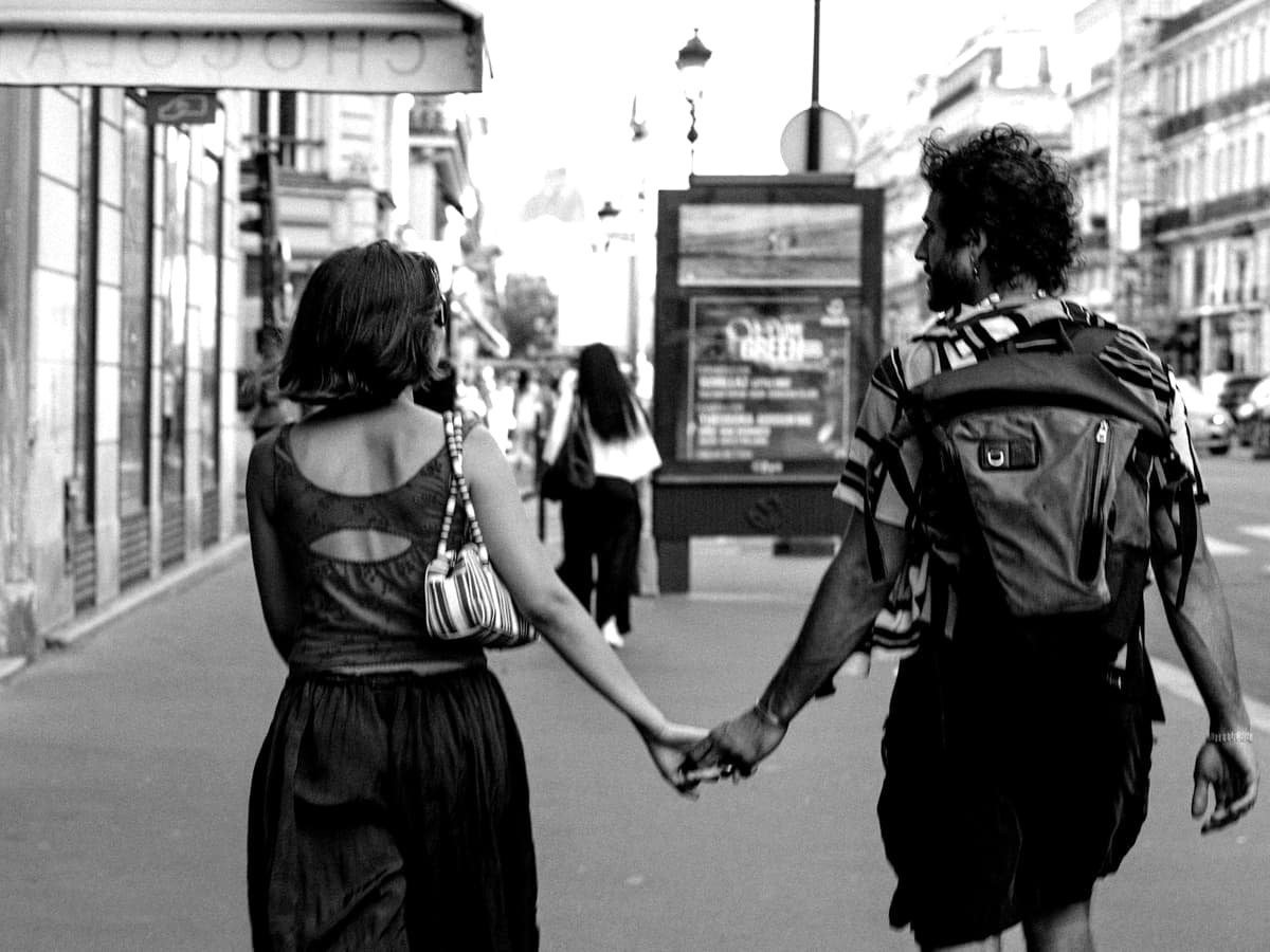 Two people holding hands walking on a city street