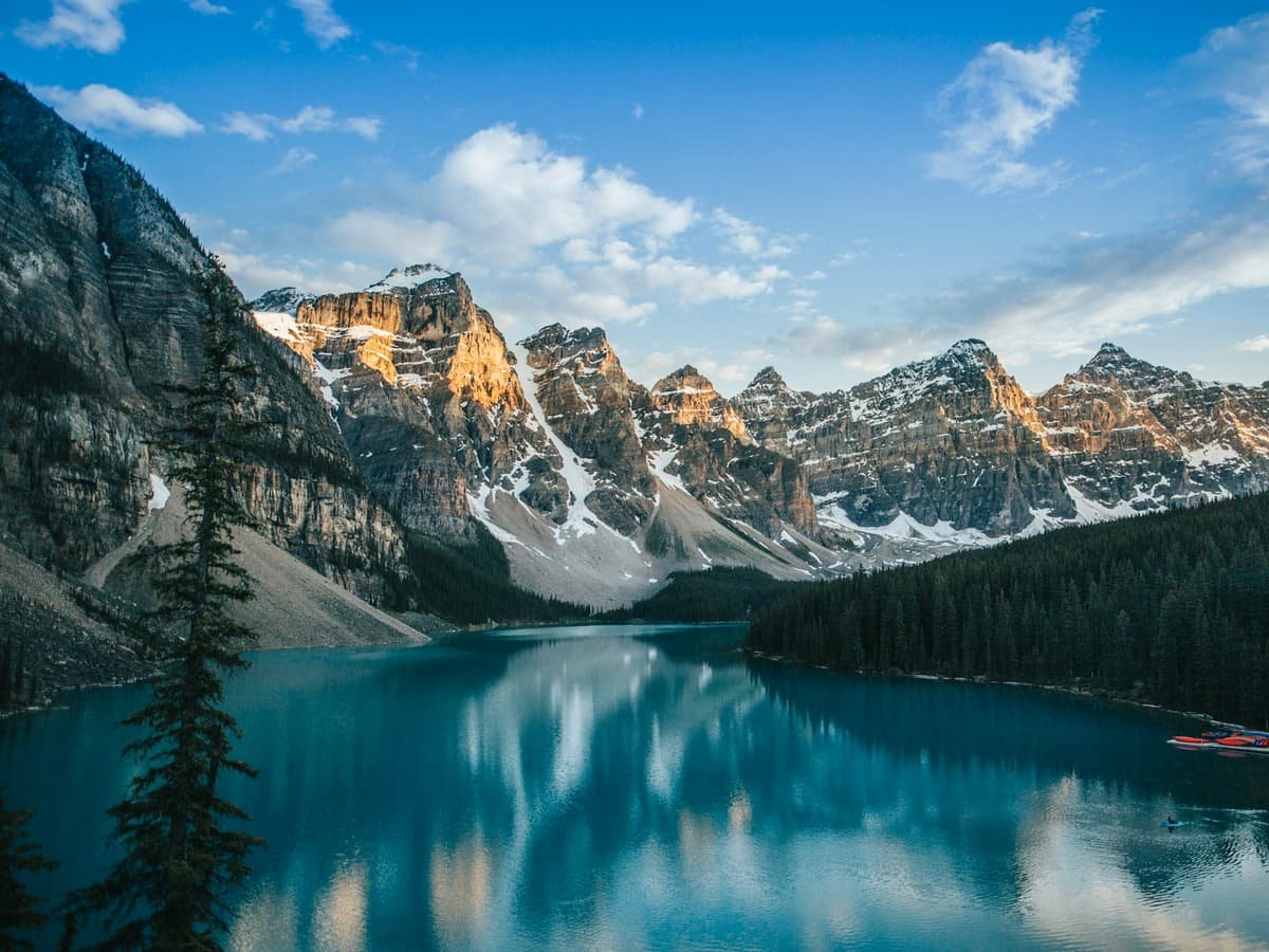 Lake near snow covered mountain under blue sky during daytime