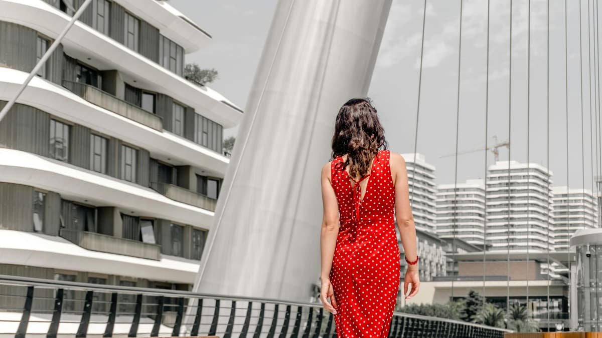 A woman in a red polka dot dress walking on a modern pedestrian bridge, date night in British Columbia