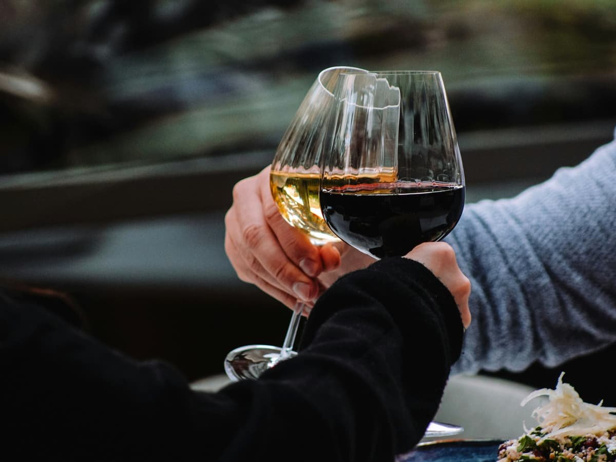 A couple of people holding hands over a glass of wine: date idea in British Columbia