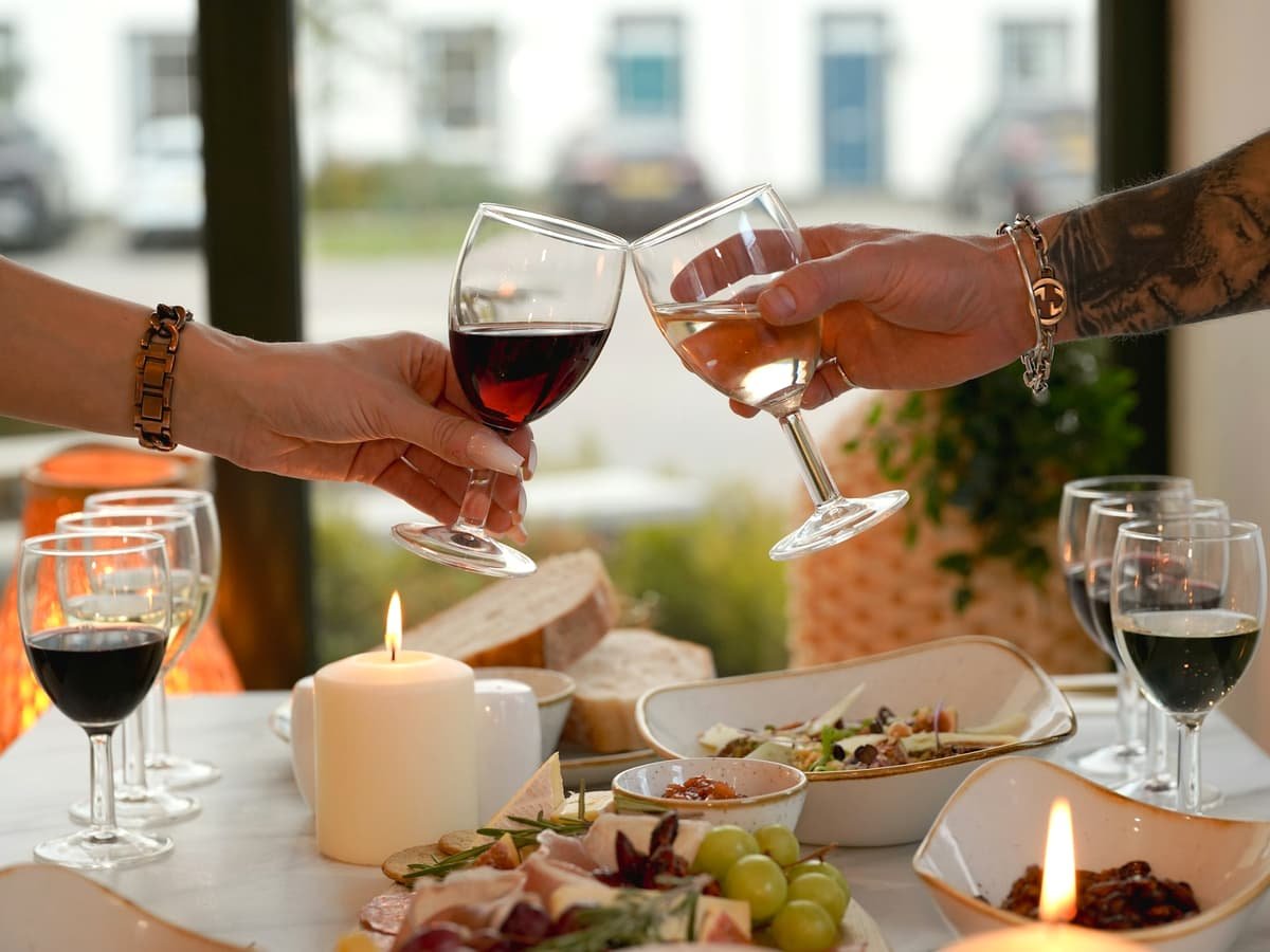Two hands clinking wine glasses over a table setting: date idea in British Columbia