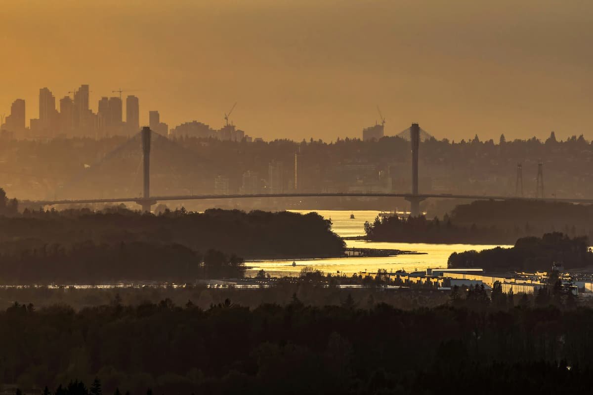 Golden sunset over a bridge, water, and distant city skyline in Surrey City Centre at dusk, British Columbia