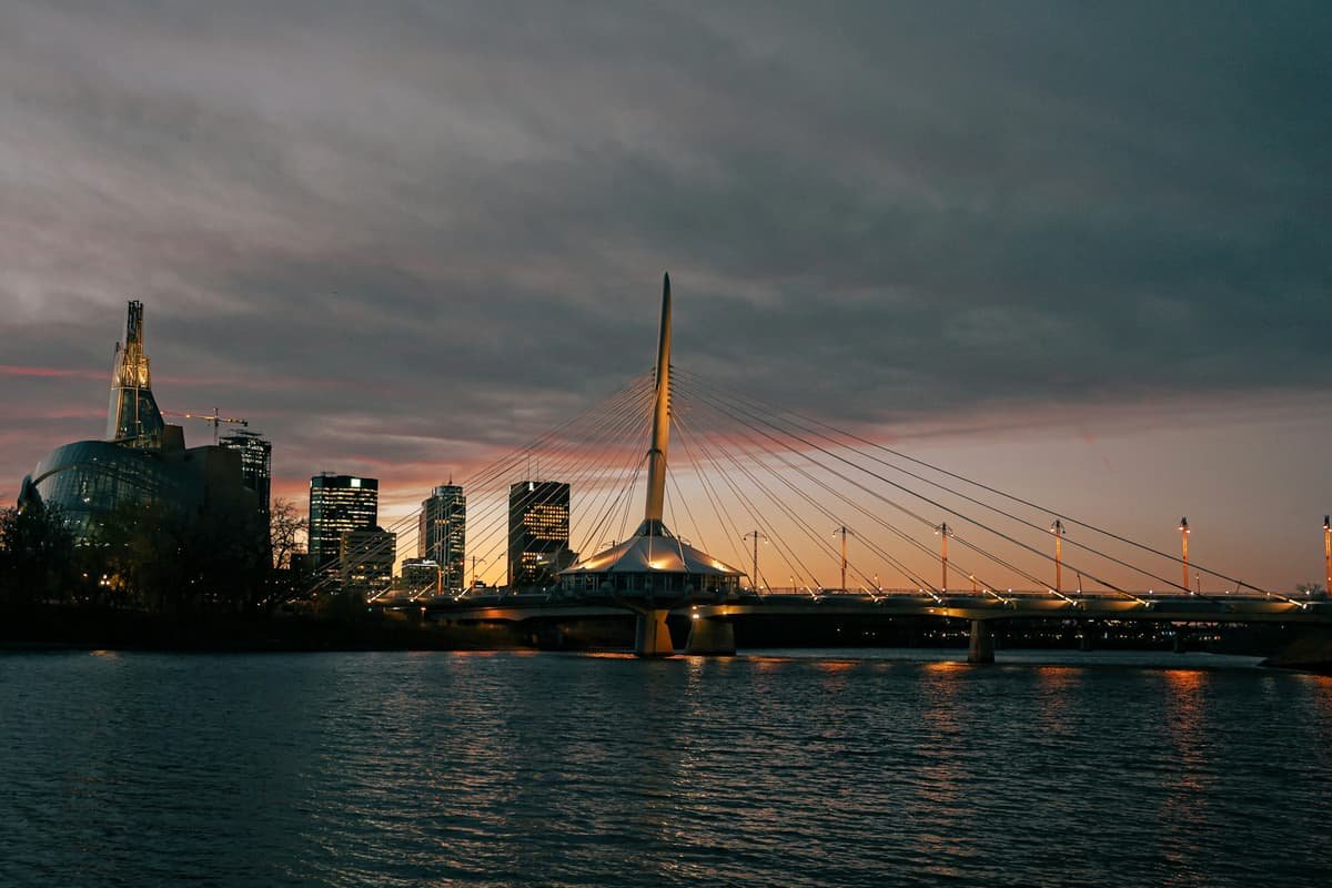 A bridge over water with a city in the background in Esplanade Riel bridge over the Red River at The Forks, Winnipeg, Manitoba