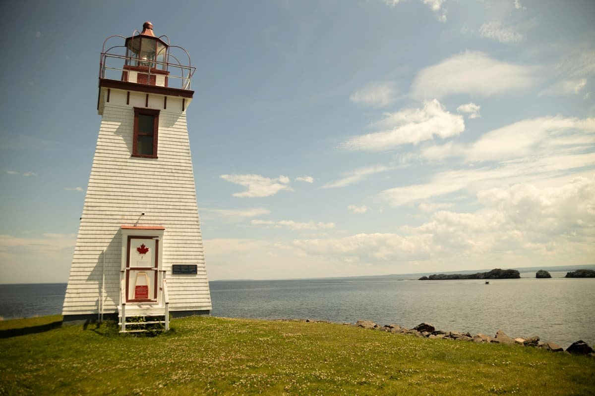 A light house sitting on top of a lush green field in Fredericton, New Brunswick