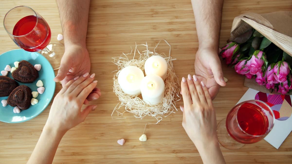 Couple holding hands over romantic dinner table with candles, date night in New Brunswick