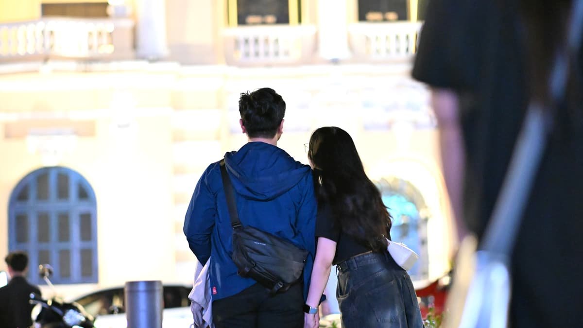 Couple holding hands with city buildings in background, date night in New Brunswick