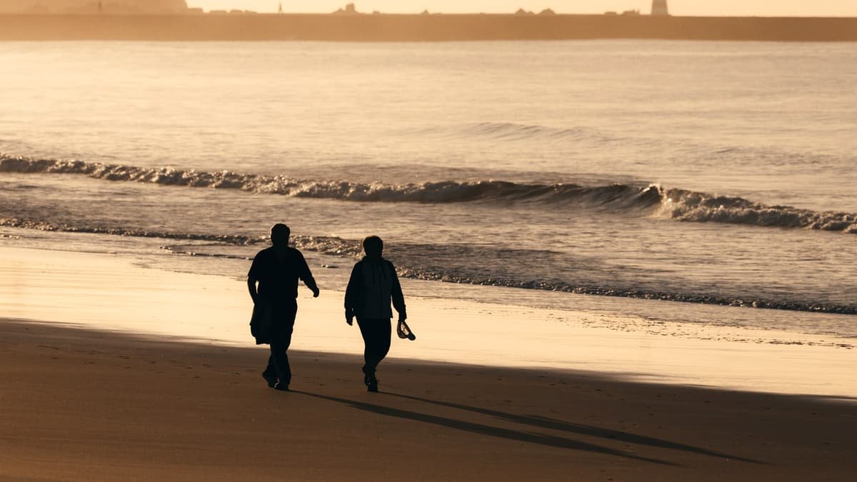 Two people walking on a beach at sunset, date night in the Northwest Territories