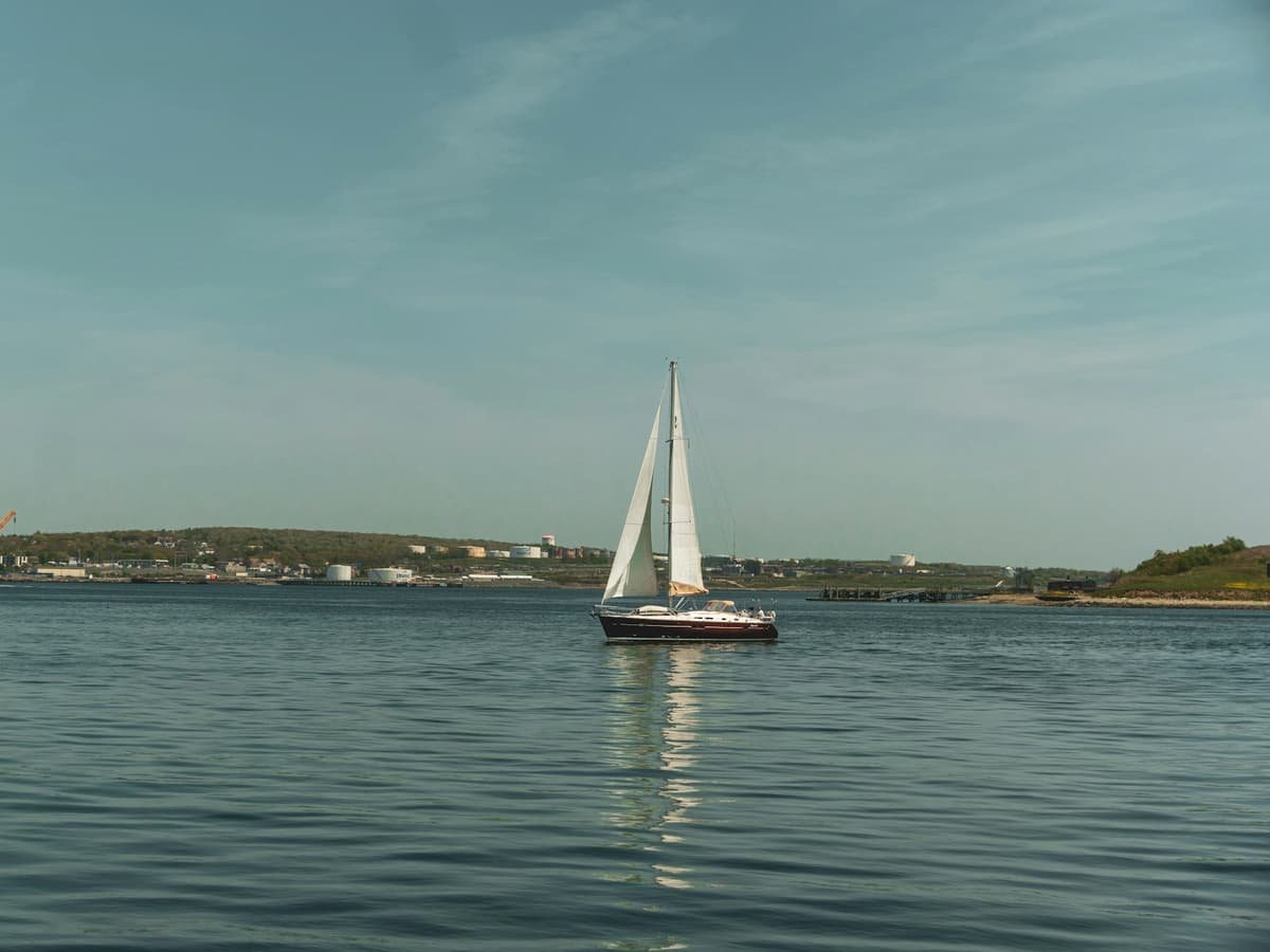 A sailboat floating on a lake with a city in the background: date idea in Nova Scotia
