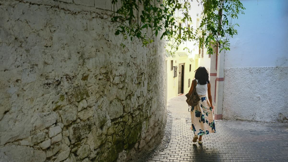 Woman walking down a sunlit cobblestone alleyway, date night in Nova Scotia