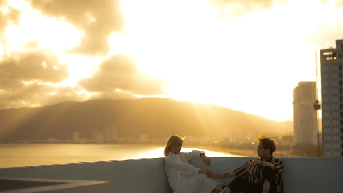 Two people sitting on a rooftop terrace against a bright golden hour sky, date night in Nova Scotia