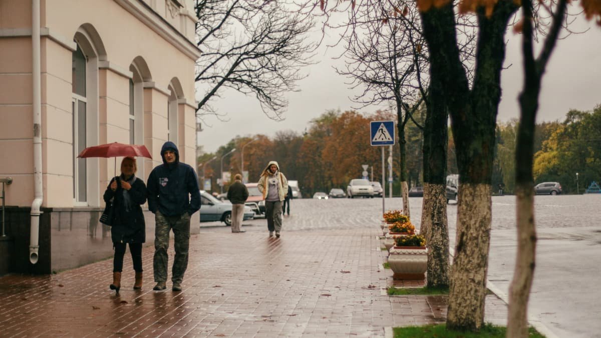 Couple walks on wet autumn sidewalk under a red umbrella, date night in Nunavut