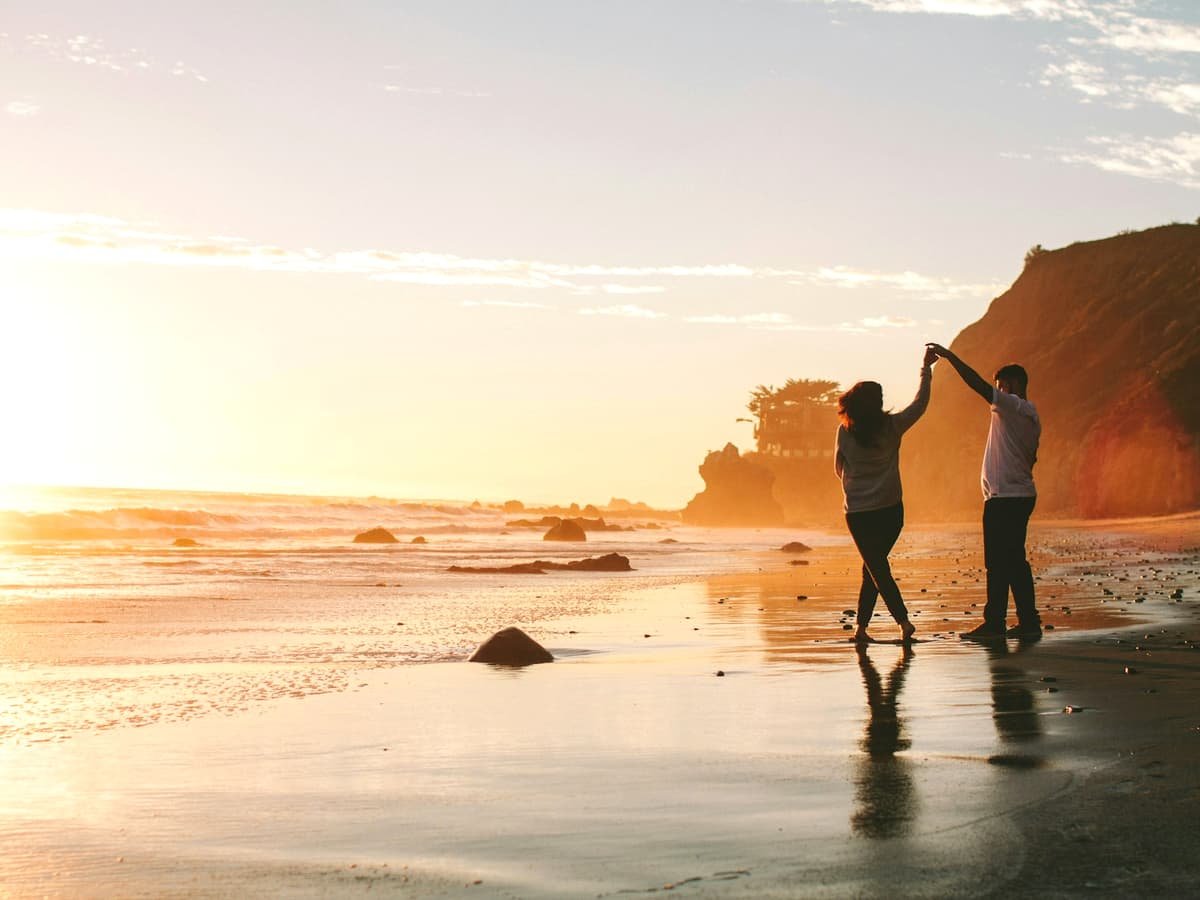 Woman and man holding hands while standing on shore during golden hour: date idea in Nunavut