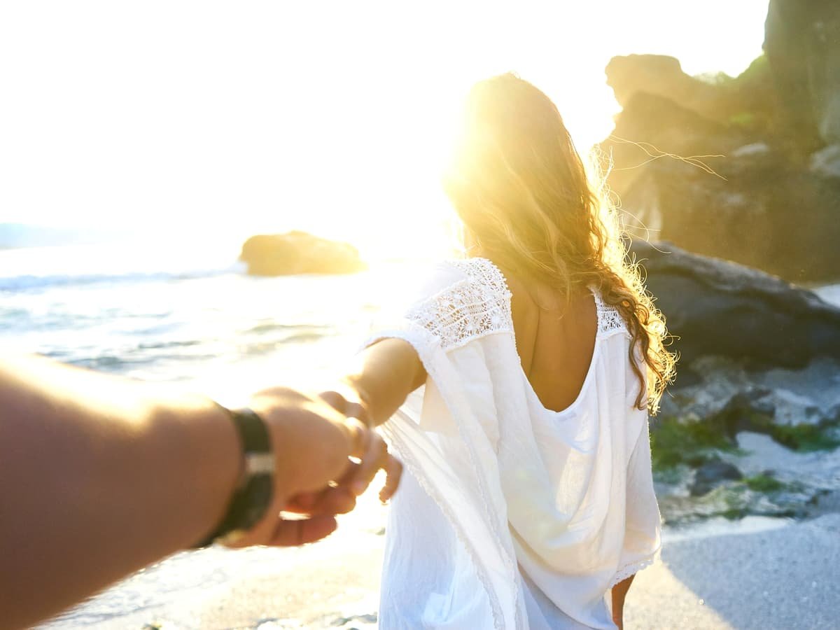 Person holding woman's hand beside sea while facing sunlight: date idea in Nunavut