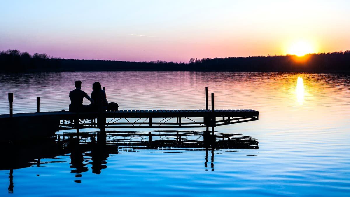 Silhouette of two persons sitting on dock, date night in Ontario
