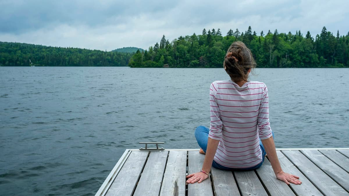 A woman sitting on a dock looking at the lake, date night in Quebec