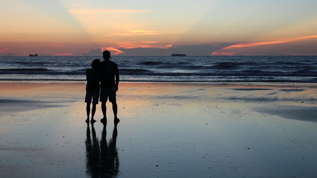 A couple of people standing on top of a beach, date night in Quebec