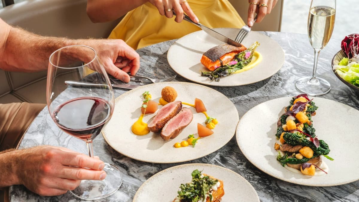 Two people dining on gourmet dishes and wine at a marble table, date night in Yukon